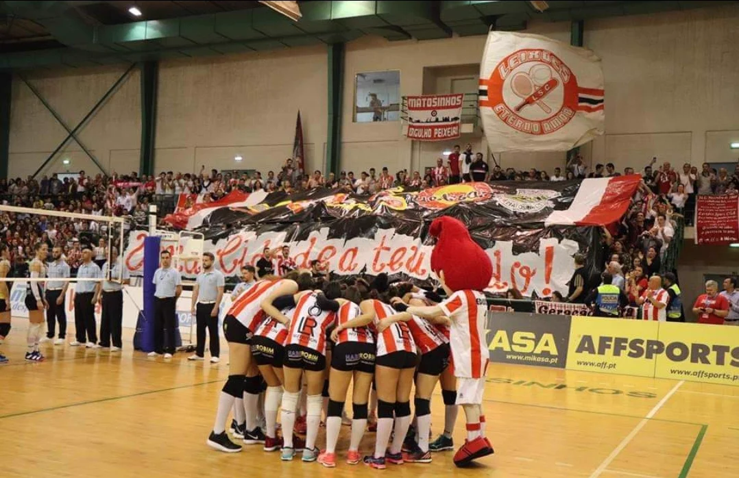 Equipa feminina de voleibol do Leixões reunida em campo perante uma bancada cheia de adeptos do Leixões