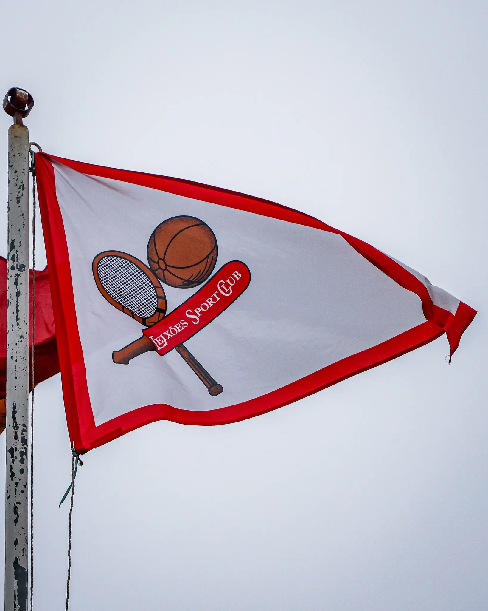 Bandeira branca com orla vermelha e o emblema do Leixões ao centro
