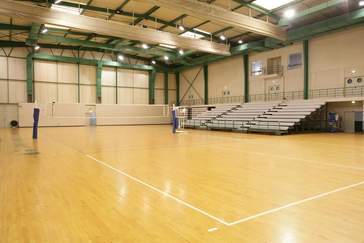 Interior da Nave Ilídio Ramos, com piso de madeira e rede de voleibol