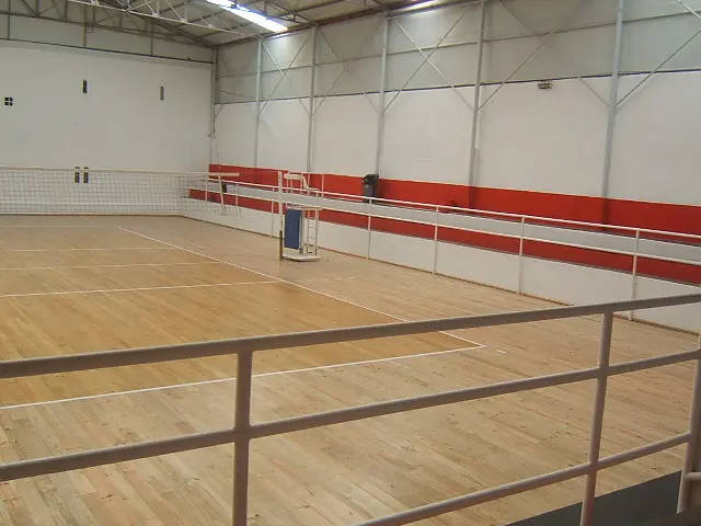 Interior do Pavilhão Siza Vieira, com piso de madeira e rede de voleibol